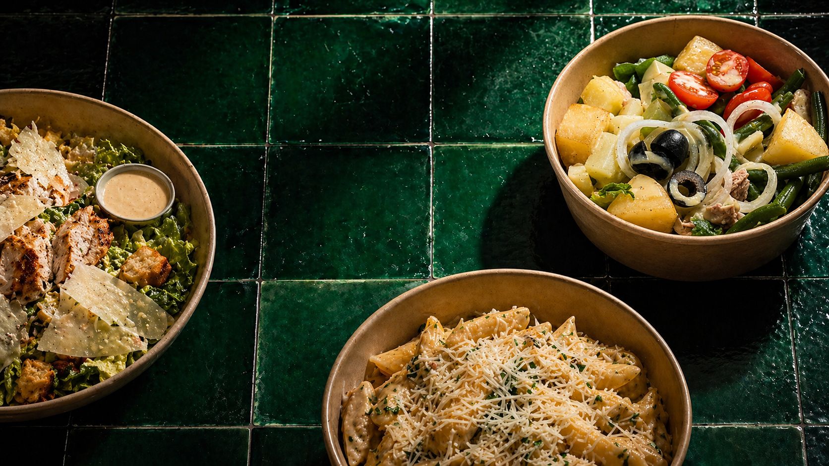 Trois plats faits maison sur une table en bois : pâtes fraîches, poulet grillé au couscous, salade de saison